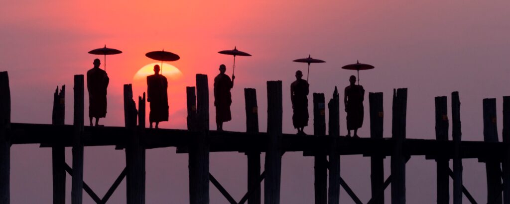 En bild på munkar på en bro i solnedgången
