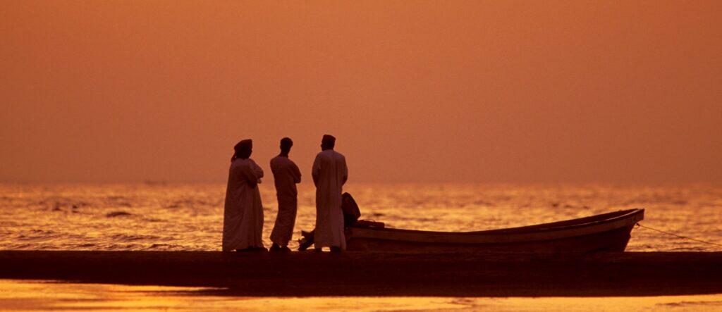 En bild på män i en båt i solnedgången