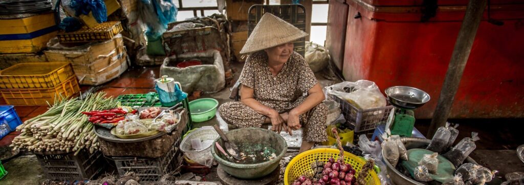 En bild på en kvinna som säljer grönsaker